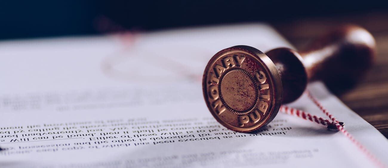 Close-up of a notary public stamp resting on a document with a red ribbon.